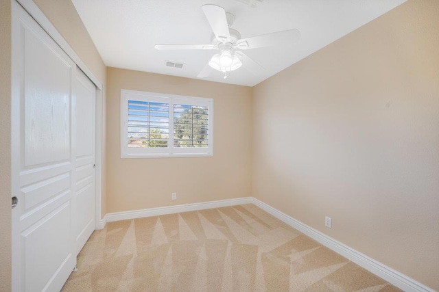 unfurnished bedroom with light colored carpet, a closet, and ceiling fan