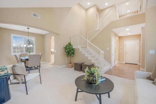 living room with light tile patterned flooring, a towering ceiling, and an inviting chandelier