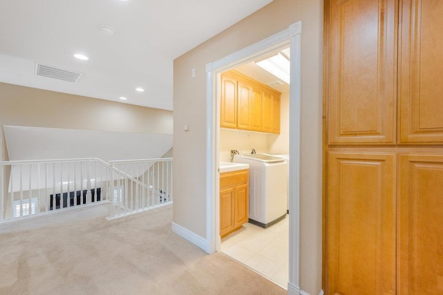 clothes washing area featuring cabinets, washer / dryer, and light carpet