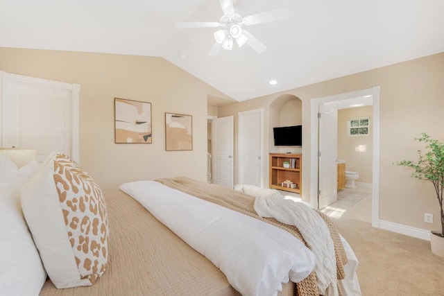 bedroom with vaulted ceiling, light carpet, ceiling fan, and ensuite bathroom