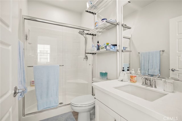 bathroom featuring toilet, vanity, and a shower with shower door