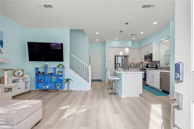 kitchen with a kitchen island, decorative light fixtures, white cabinetry, a kitchen bar, and stainless steel appliances