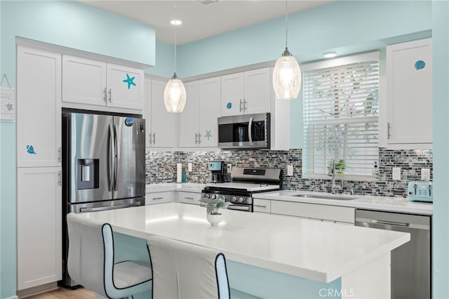 kitchen with stainless steel appliances, white cabinetry, sink, and pendant lighting