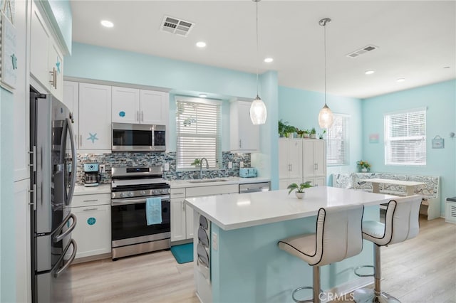 kitchen with hanging light fixtures, sink, white cabinets, and appliances with stainless steel finishes