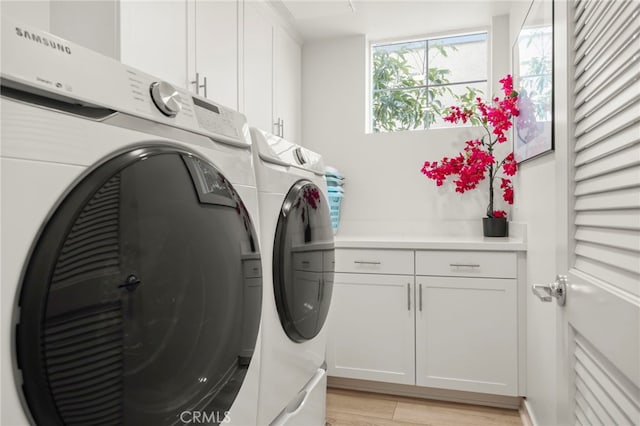 laundry room with cabinets, independent washer and dryer, and light hardwood / wood-style flooring