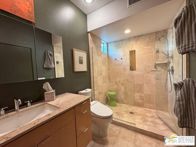 bathroom with tiled shower, vanity, toilet, and tile patterned flooring