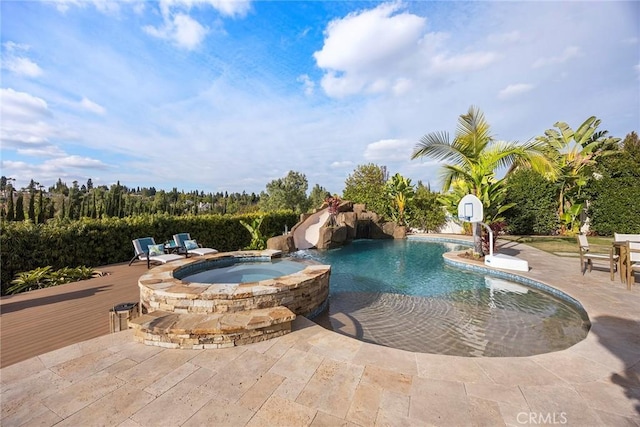 view of pool featuring a patio area, a water slide, and a pool with connected hot tub