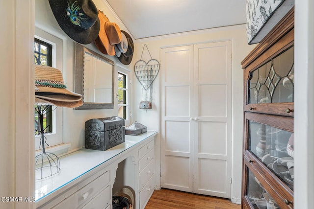 kitchen with built in desk, white cabinets, and light wood-type flooring