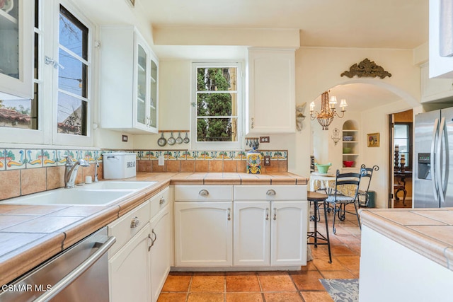 kitchen featuring stainless steel appliances, white cabinetry, sink, and tile countertops