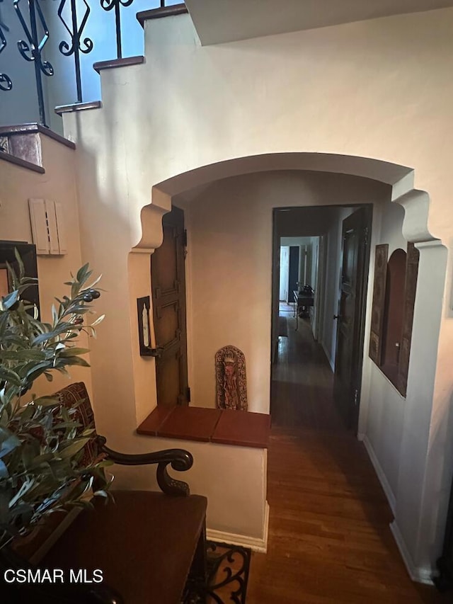 hallway featuring dark wood-type flooring and a towering ceiling