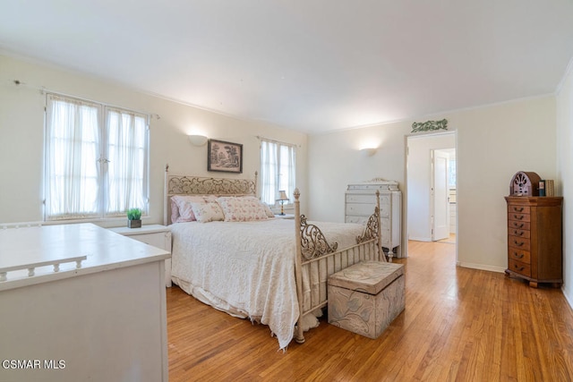 bedroom with crown molding, multiple windows, and light wood-type flooring