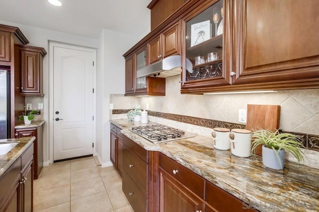 kitchen with tasteful backsplash, stainless steel appliances, light stone counters, and light tile patterned floors