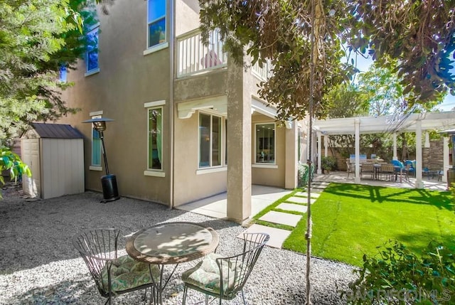 rear view of house with a storage shed, a patio, a lawn, and a pergola