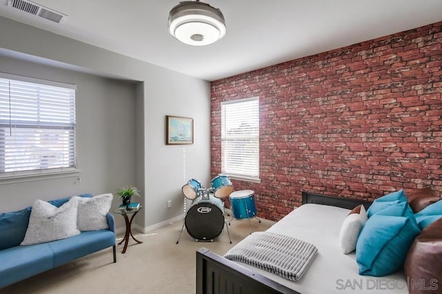 bedroom featuring light colored carpet and brick wall