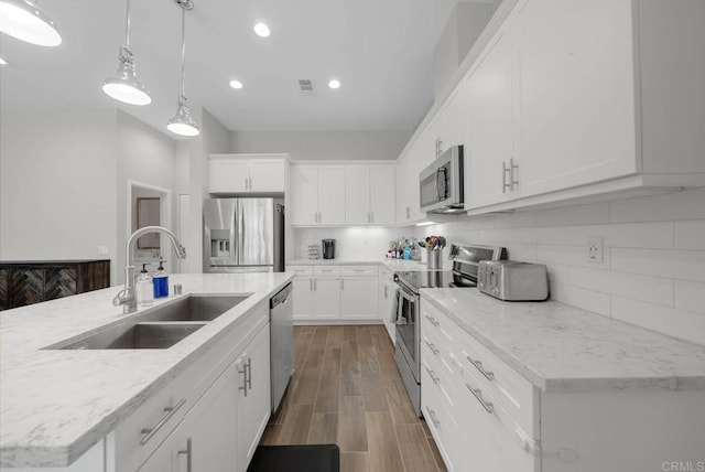 kitchen featuring appliances with stainless steel finishes, sink, pendant lighting, and white cabinets