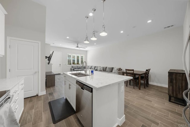 kitchen featuring sink, dishwasher, white cabinetry, hanging light fixtures, and a center island with sink