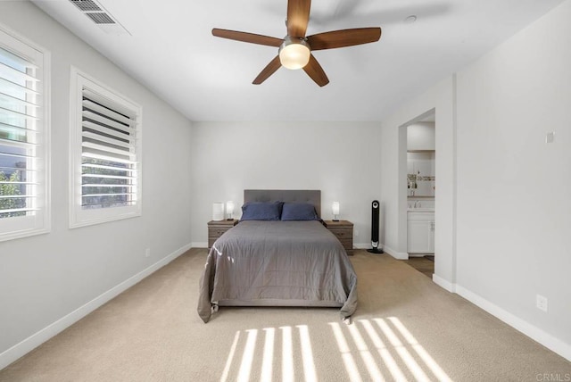 carpeted bedroom with ensuite bathroom and ceiling fan