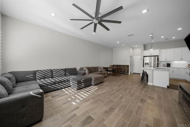 living room featuring sink, ceiling fan, and light hardwood / wood-style flooring