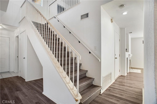 stairs with visible vents, a towering ceiling, and wood finished floors