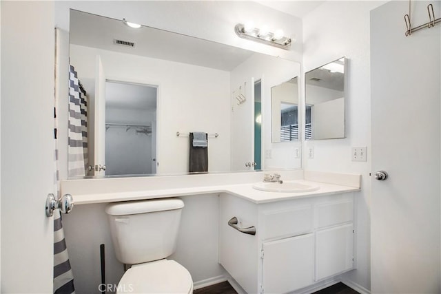 bathroom with toilet, vanity, and visible vents