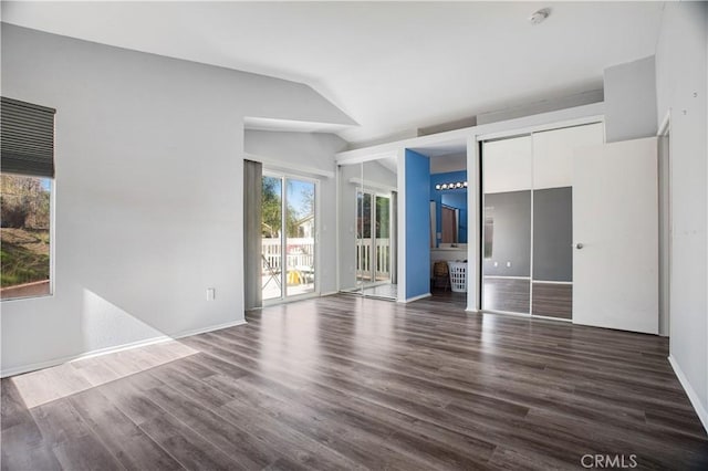 unfurnished bedroom with lofted ceiling, dark wood-style flooring, baseboards, access to exterior, and two closets