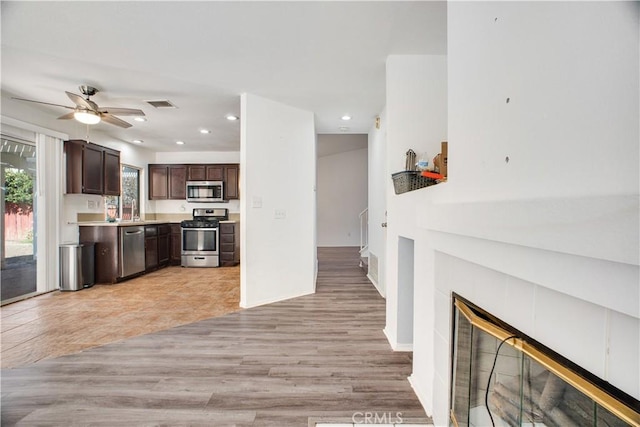 kitchen with dark brown cabinetry, a fireplace, visible vents, light countertops, and appliances with stainless steel finishes