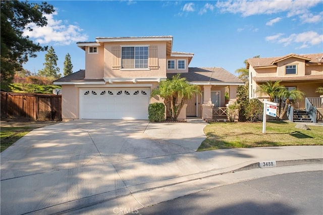 traditional home featuring a garage, fence, concrete driveway, stucco siding, and a front lawn