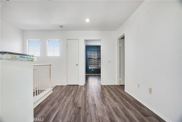 spare room featuring baseboards and dark wood-style flooring