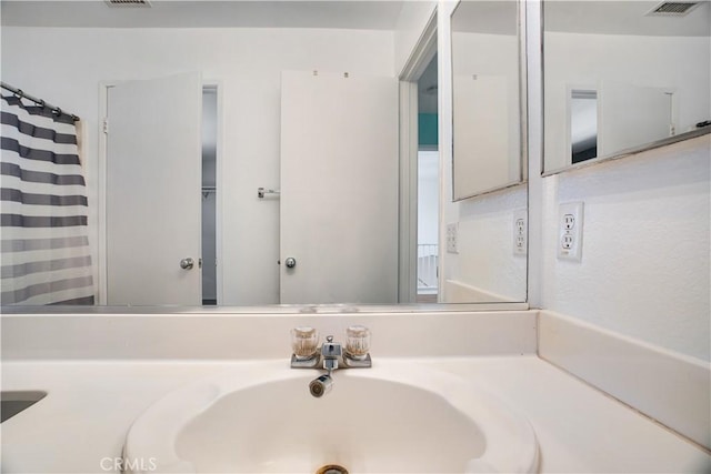 full bathroom with curtained shower, visible vents, and a sink