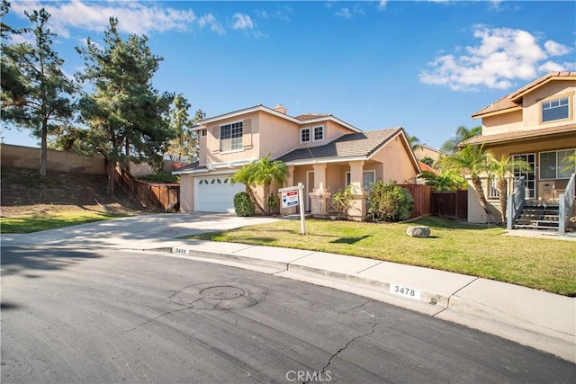 traditional-style house with stucco siding, concrete driveway, an attached garage, a front yard, and fence