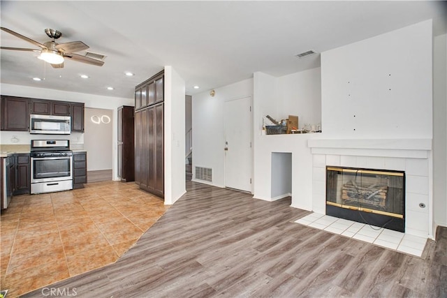 kitchen featuring stainless steel appliances, light countertops, dark brown cabinetry, and visible vents