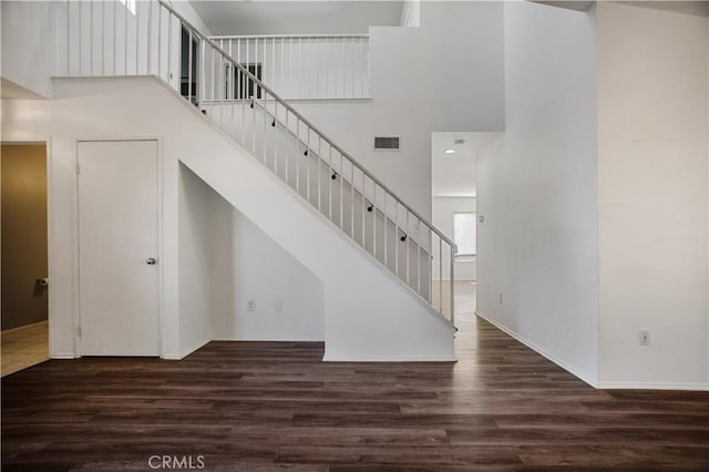 stairway with visible vents, a high ceiling, and wood finished floors