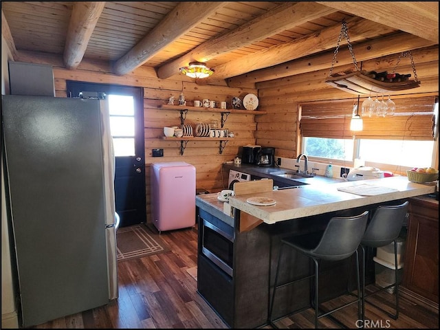 kitchen featuring a breakfast bar, sink, stainless steel refrigerator, dark hardwood / wood-style floors, and kitchen peninsula