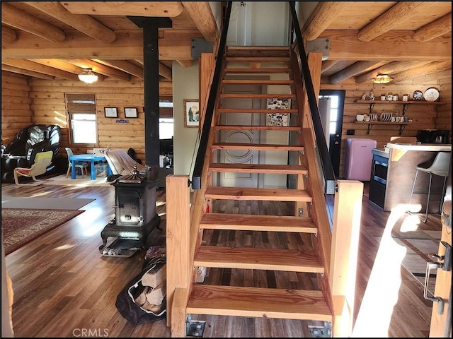 stairs featuring beamed ceiling, wooden walls, and hardwood / wood-style floors