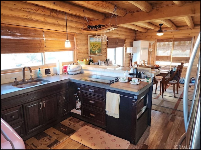 kitchen with pendant lighting, sink, dark wood-type flooring, wooden walls, and decorative backsplash