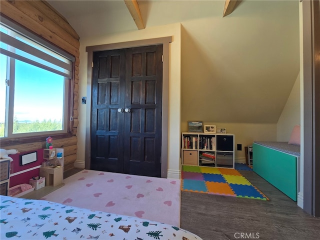 bedroom with log walls, a closet, and vaulted ceiling with beams