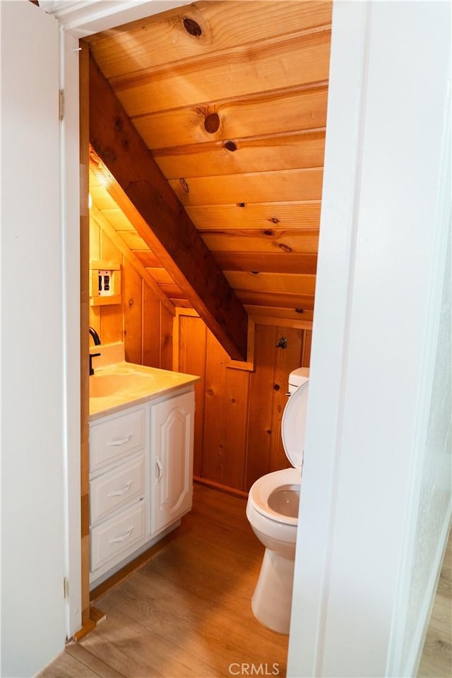 bathroom with toilet, wood walls, wood ceiling, vanity, and hardwood / wood-style flooring