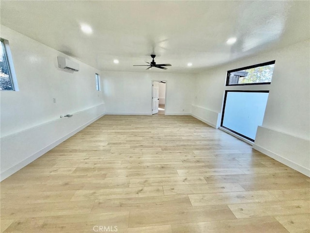 unfurnished room featuring a wall unit AC, ceiling fan, and light wood-type flooring