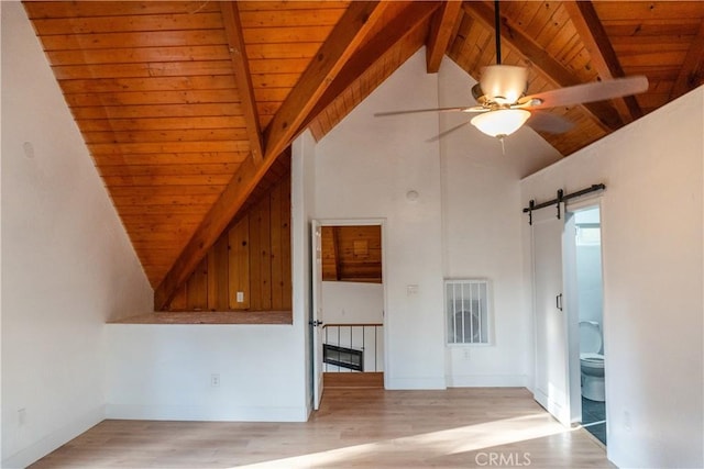 additional living space featuring lofted ceiling with beams, light hardwood / wood-style flooring, wooden ceiling, and a barn door