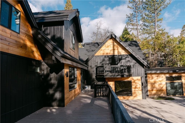 back of house featuring a wooden deck and a balcony