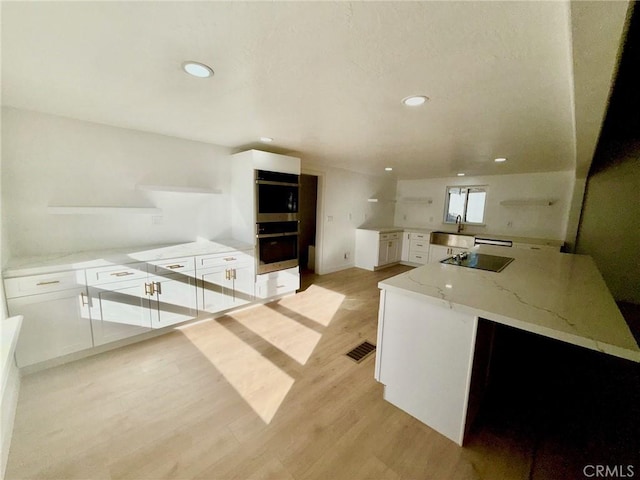 kitchen featuring light stone counters, black electric cooktop, kitchen peninsula, and white cabinets