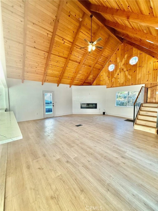 unfurnished living room with beam ceiling, ceiling fan, wood ceiling, and light wood-type flooring