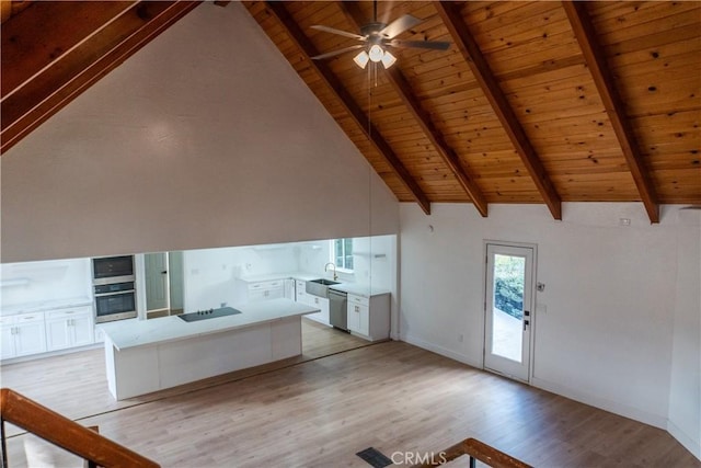 kitchen featuring sink, high vaulted ceiling, stainless steel dishwasher, and white cabinets