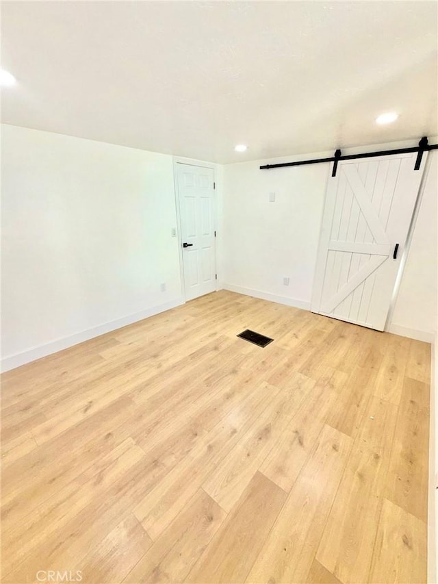 spare room featuring a barn door and light hardwood / wood-style flooring