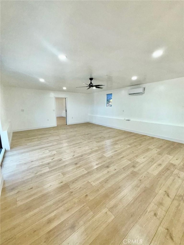 unfurnished living room featuring ceiling fan, a wall unit AC, and light hardwood / wood-style flooring