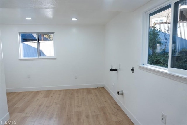 clothes washing area featuring hookup for an electric dryer and light wood-type flooring