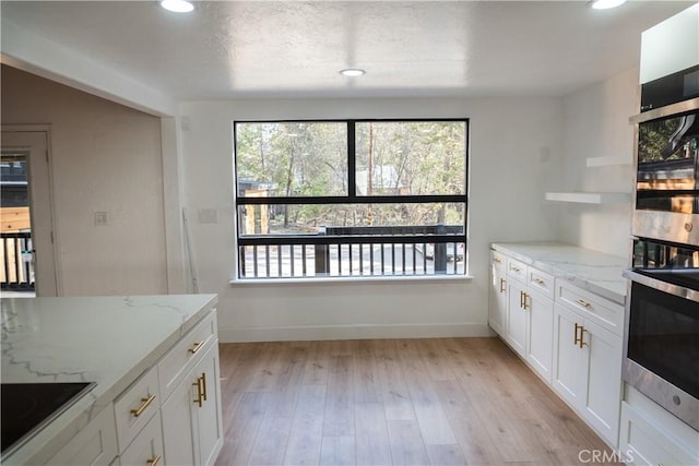 kitchen featuring light stone counters, plenty of natural light, and white cabinets