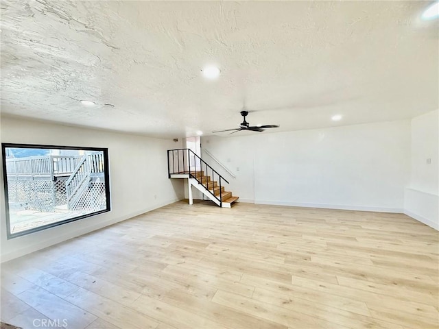 unfurnished living room featuring ceiling fan, a textured ceiling, and light wood-type flooring