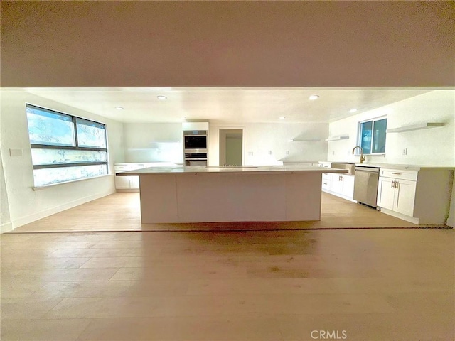 kitchen with light hardwood / wood-style flooring, stainless steel appliances, white cabinets, and a kitchen island