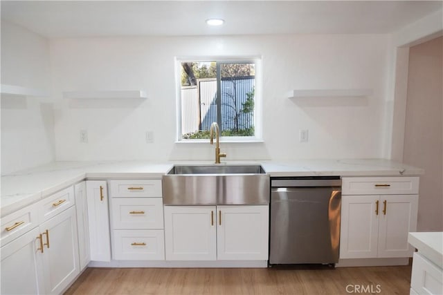 kitchen with sink, light stone counters, white cabinetry, light wood-type flooring, and stainless steel dishwasher